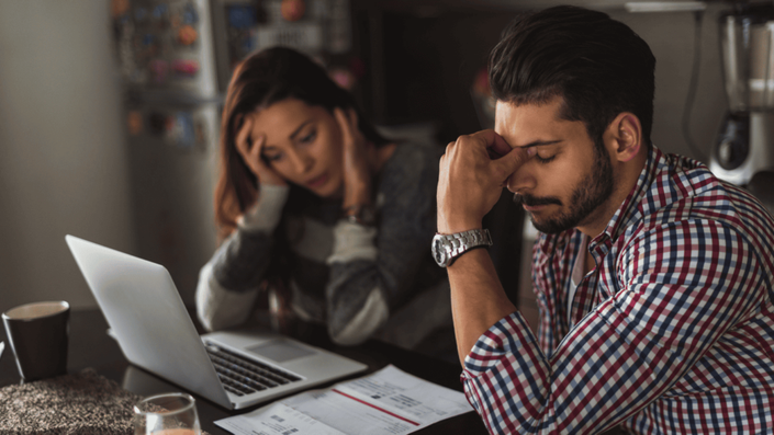 duas pessoas no notebook preocupadas com suas dívidas