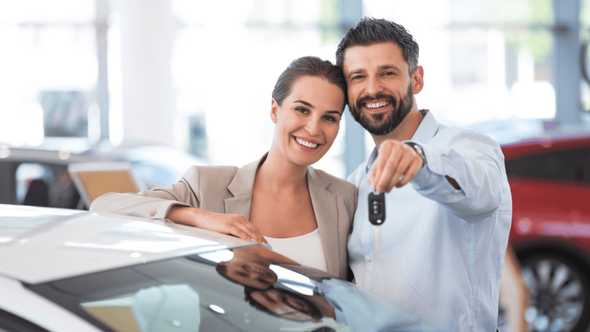 pareja sonriente con las llaves del auto en la mano