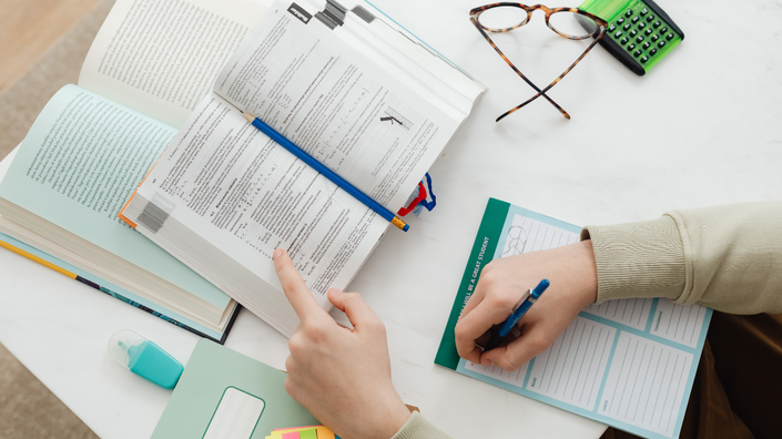 Mesa com livro de finanças e anotações, representando o autoconhecimento financeiro e o impacto do dinheiro