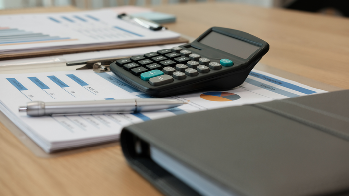 Documentos e calculadora em uma mesa, simbolizando a análise de empréstimos para estudantes