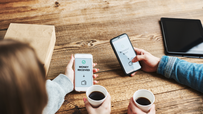 Dos personas tomando un café y transfiriendo dinero online