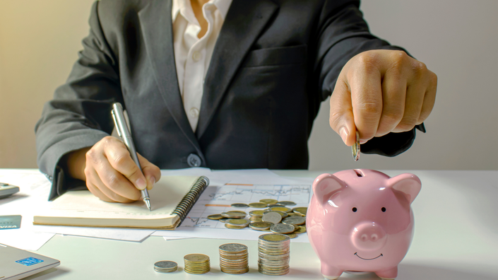 Cofrinho sendo preenchido com moedas, simbolizando economia e a importância da liberdade financeira
