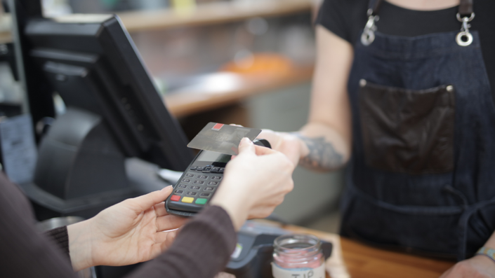 Una pareja utilizando una tarjeta de crédito en una tienda, revisando ofertas.