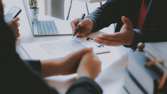 Personas revisando documentos y firmando un contrato de préstamo en México. La escena representa la importancia de leer los términos antes de adquirir financiamiento.