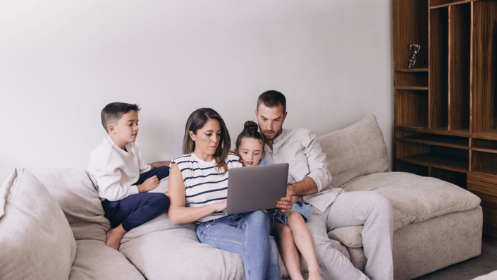 Padres e hijos planificando juntos su presupuesto familiar, ajustando ingresos y gastos en su laptop.