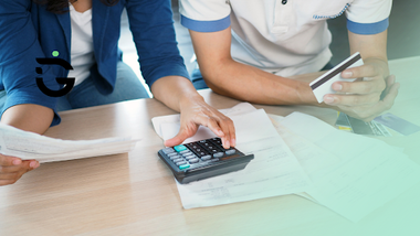 personas con calculadora y papeles sobre la mesa calculando gastos de tarjeta de crédito