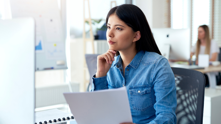 mulher no computador com papéis na mão